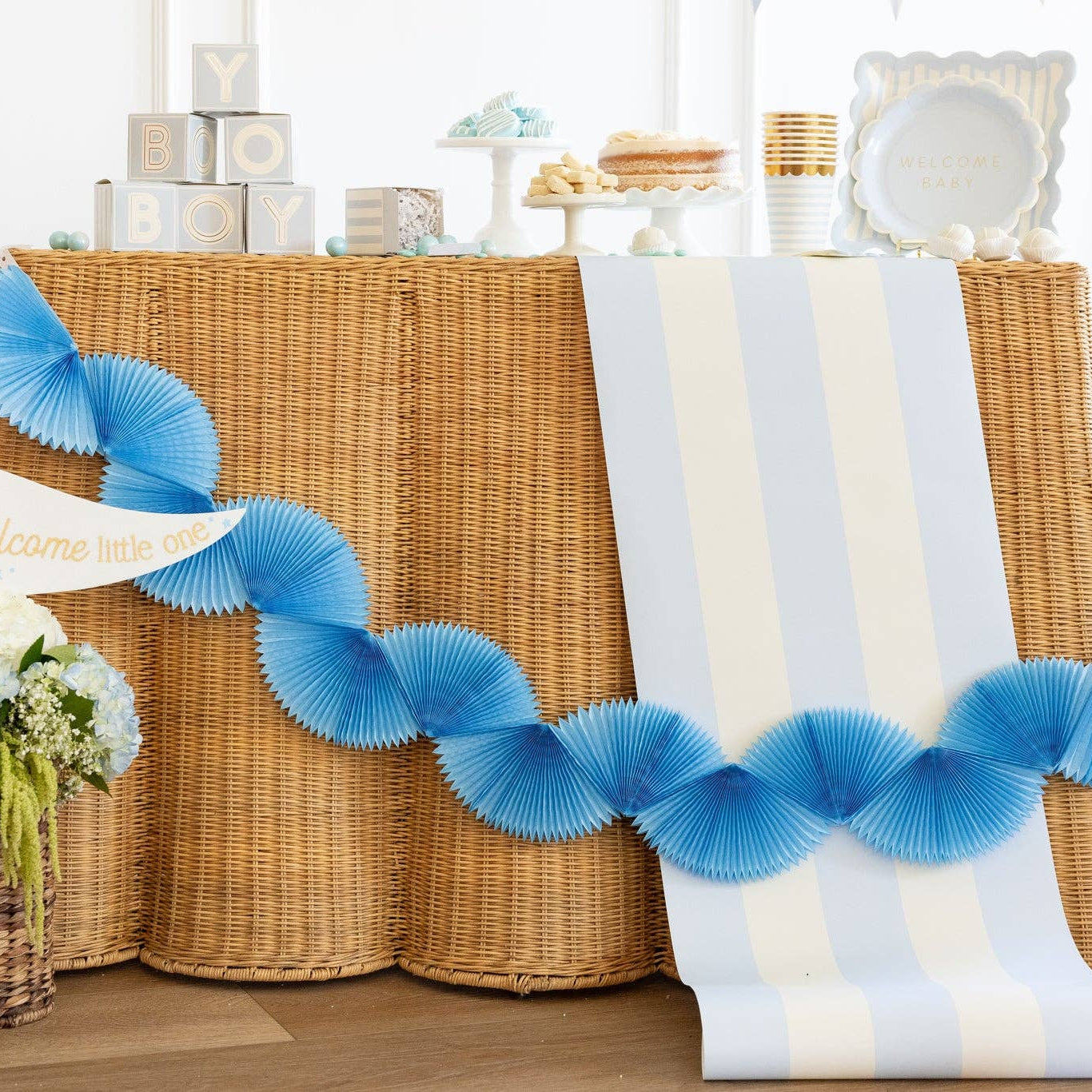 Blue tissue bunting banner draped across baby shower table decor

