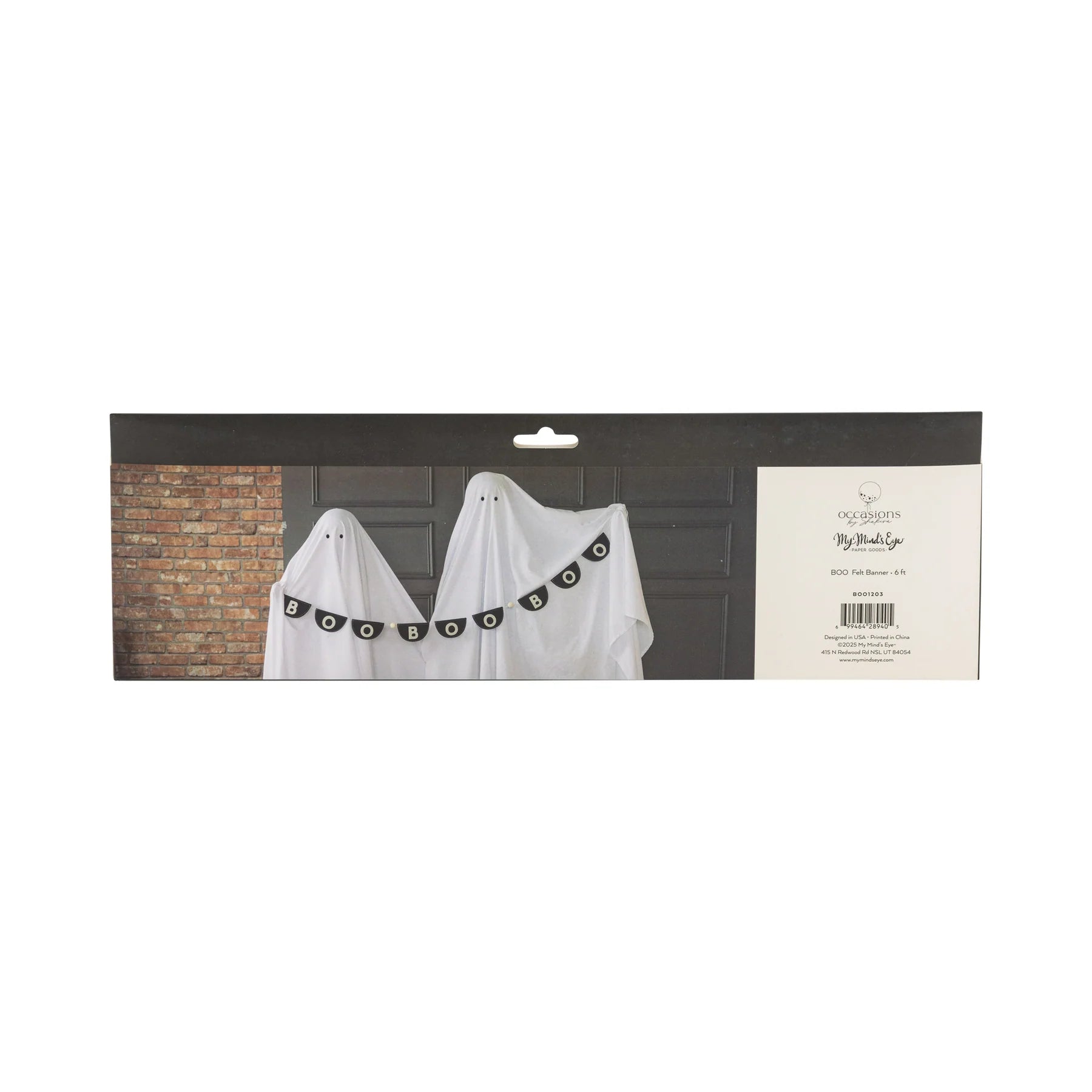 Retail back-of-pack image for Boo felt Halloween banner. Long black header card shows three sheet-clad “ghost” kids in front of gray paneled doors; the six-foot felt pennant garland spells BOO multiple times across their chests, cream pom-poms in between. Right panel lists Occasions by Shakira™ and My Mind’s Eye logos, barcode, item code and 6 ft length, giving online shoppers scale, branding and care info at a glance.