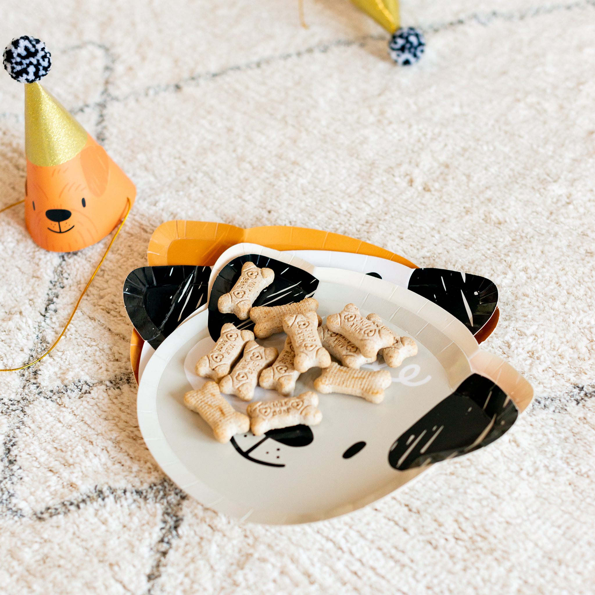 Dog treat plate with Bow Wow party hat nearby at puppy party