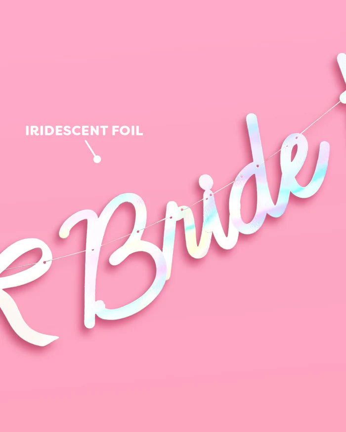 Close-up of iridescent foil finish on Bride to Be banner lettering showing color shift on pink background