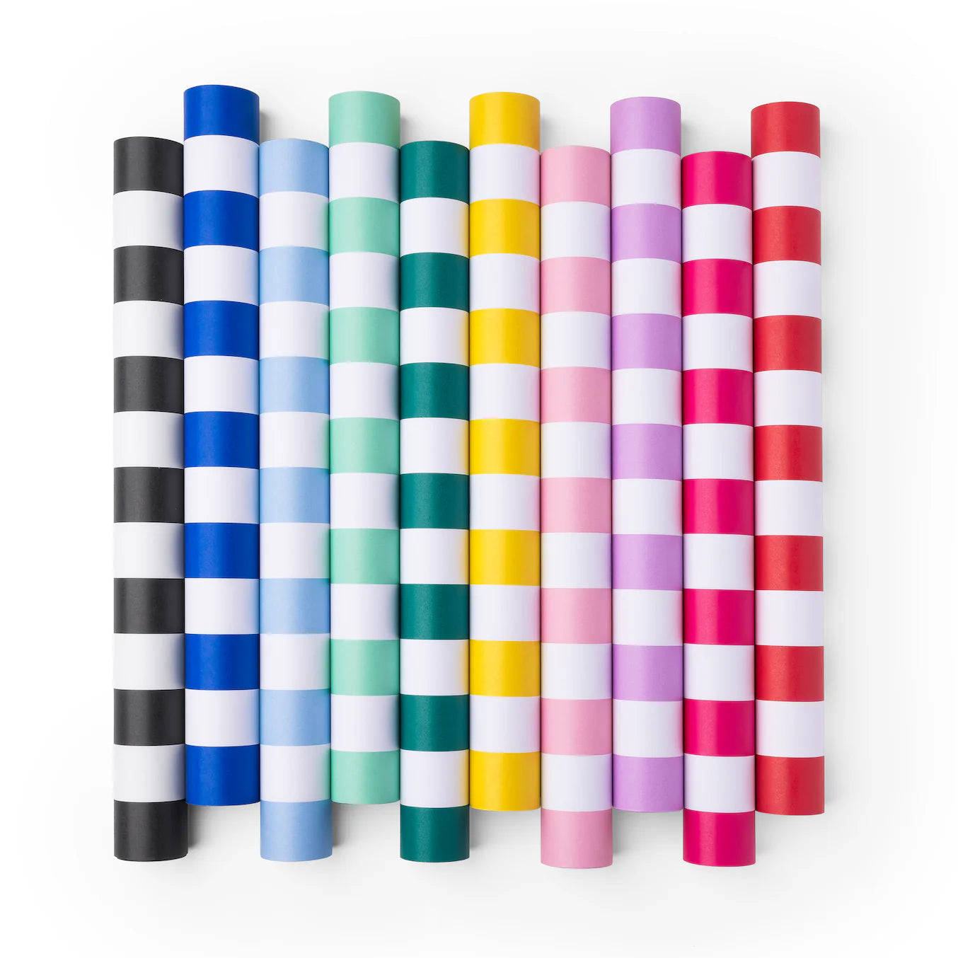 Overhead shot of ten rolled paper table runners in rainbow cabana stripes, sky‑blue roll third from left.