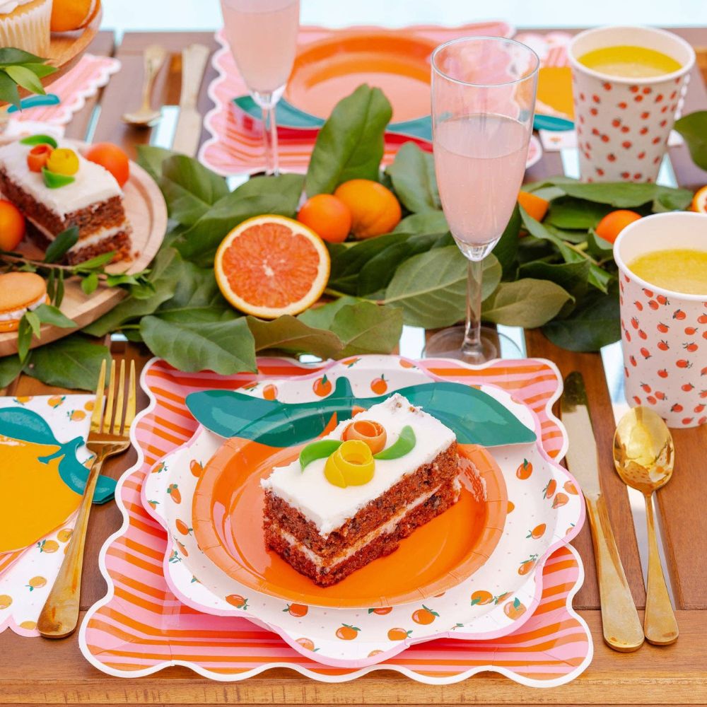 Slice of cake served on an orange shaped paper plate.
