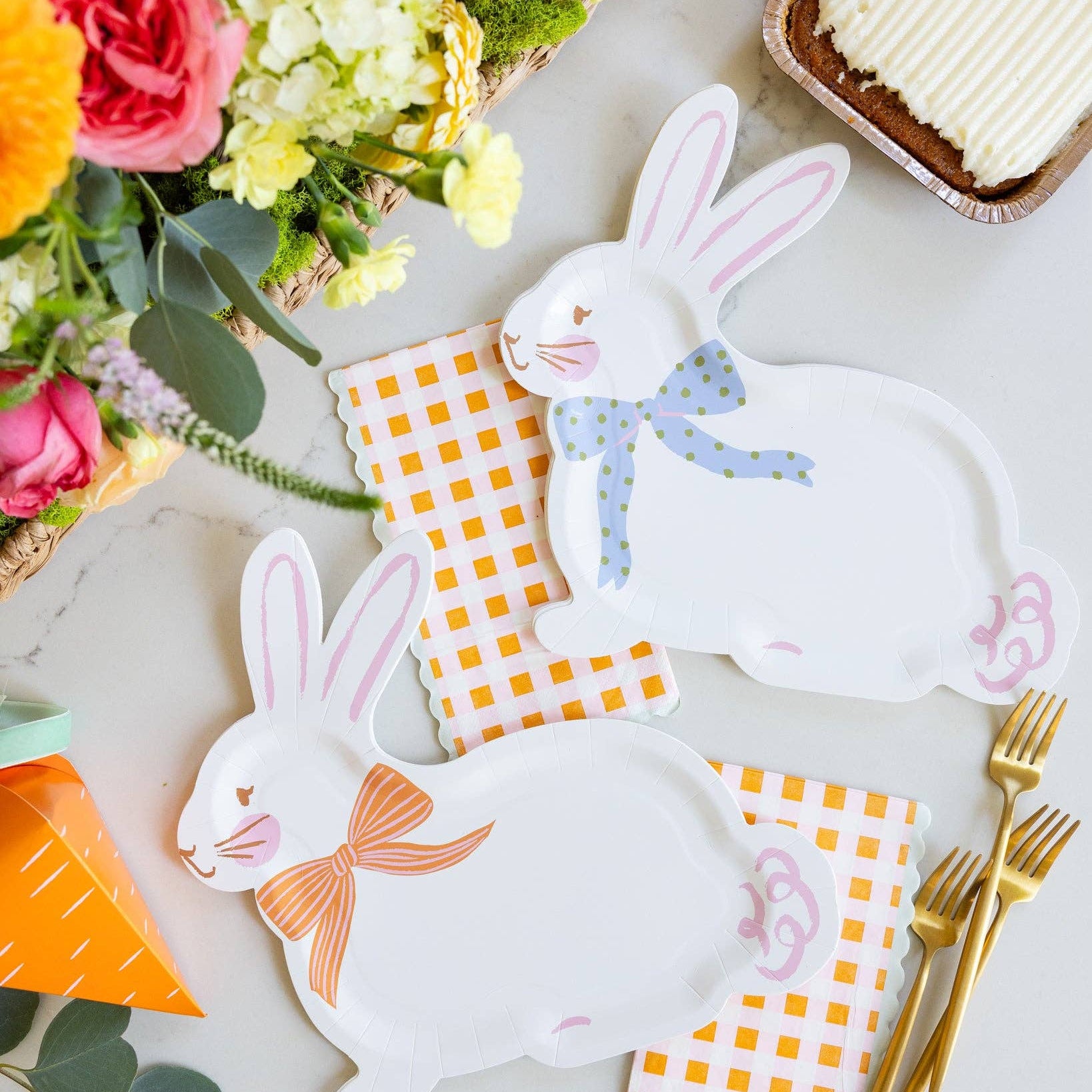Carrot patch gingham napkins layered under bunny plates in a styled Easter tablescape with gold flatware and spring flowers