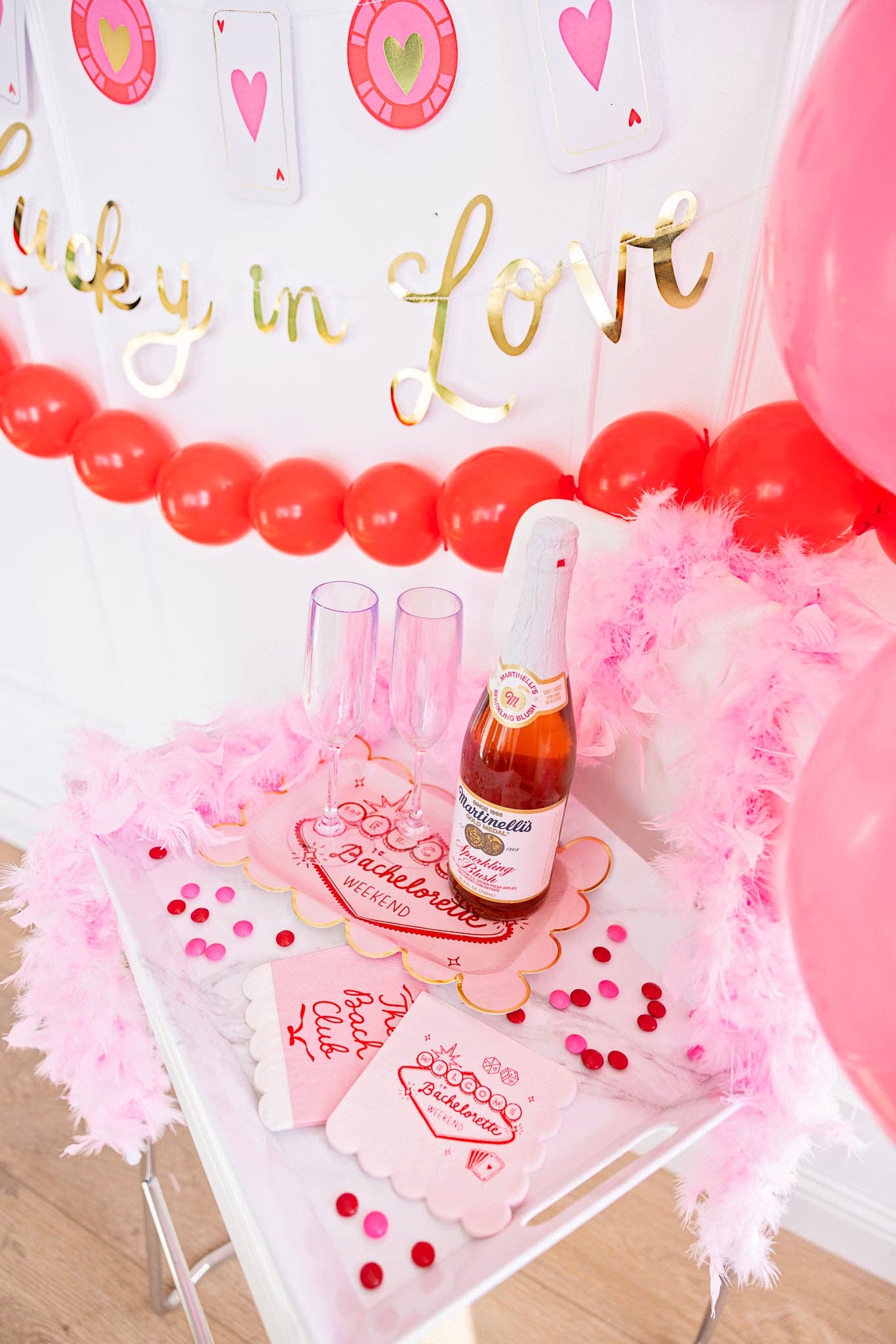 Lucky in Love plates styled on a white bar cart with champagne and a casino theme bachelorette banner.