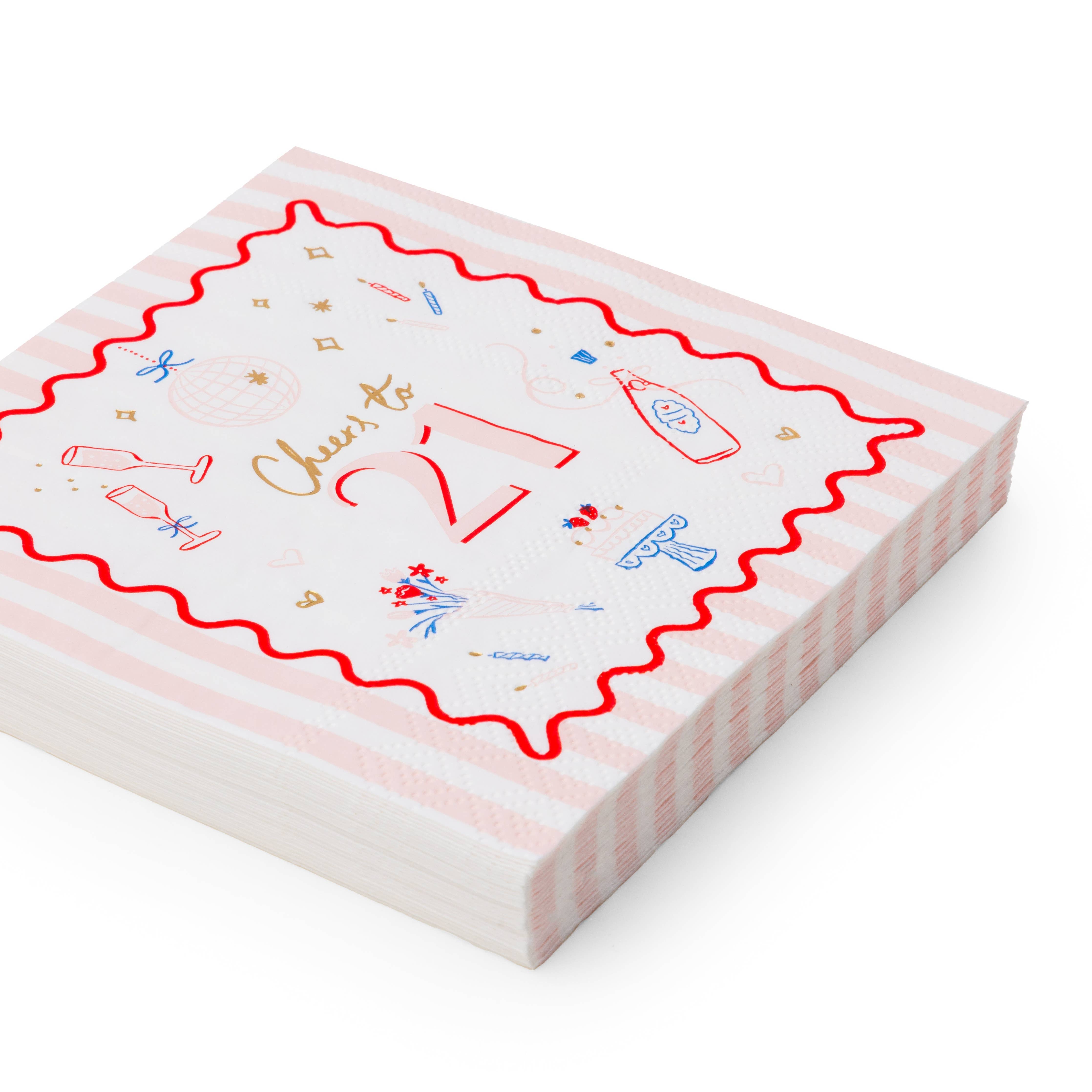 Angled stack of pink striped Cheers to 21 birthday cocktail napkins with red wavy border and champagne cake icons on white background