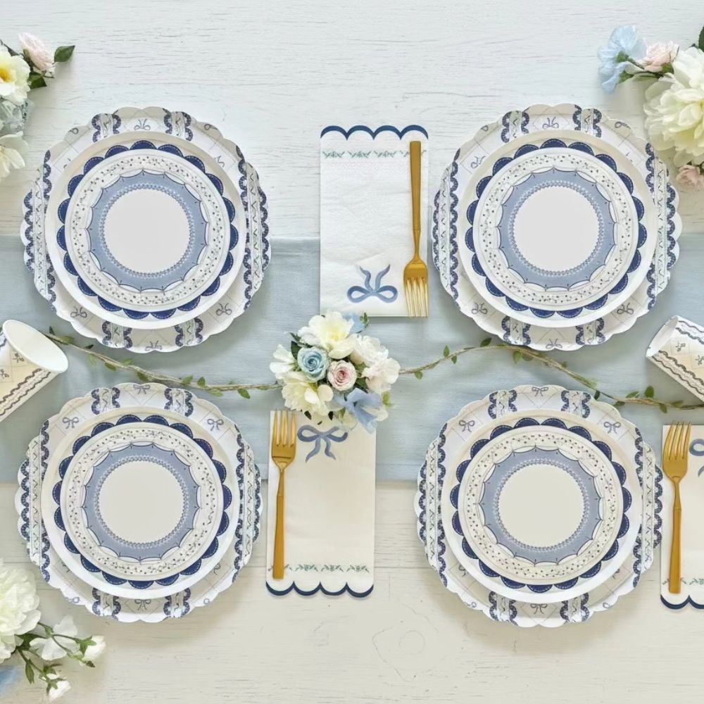 Symmetrical table arrangement with four blue ribbon place settings and gold forks