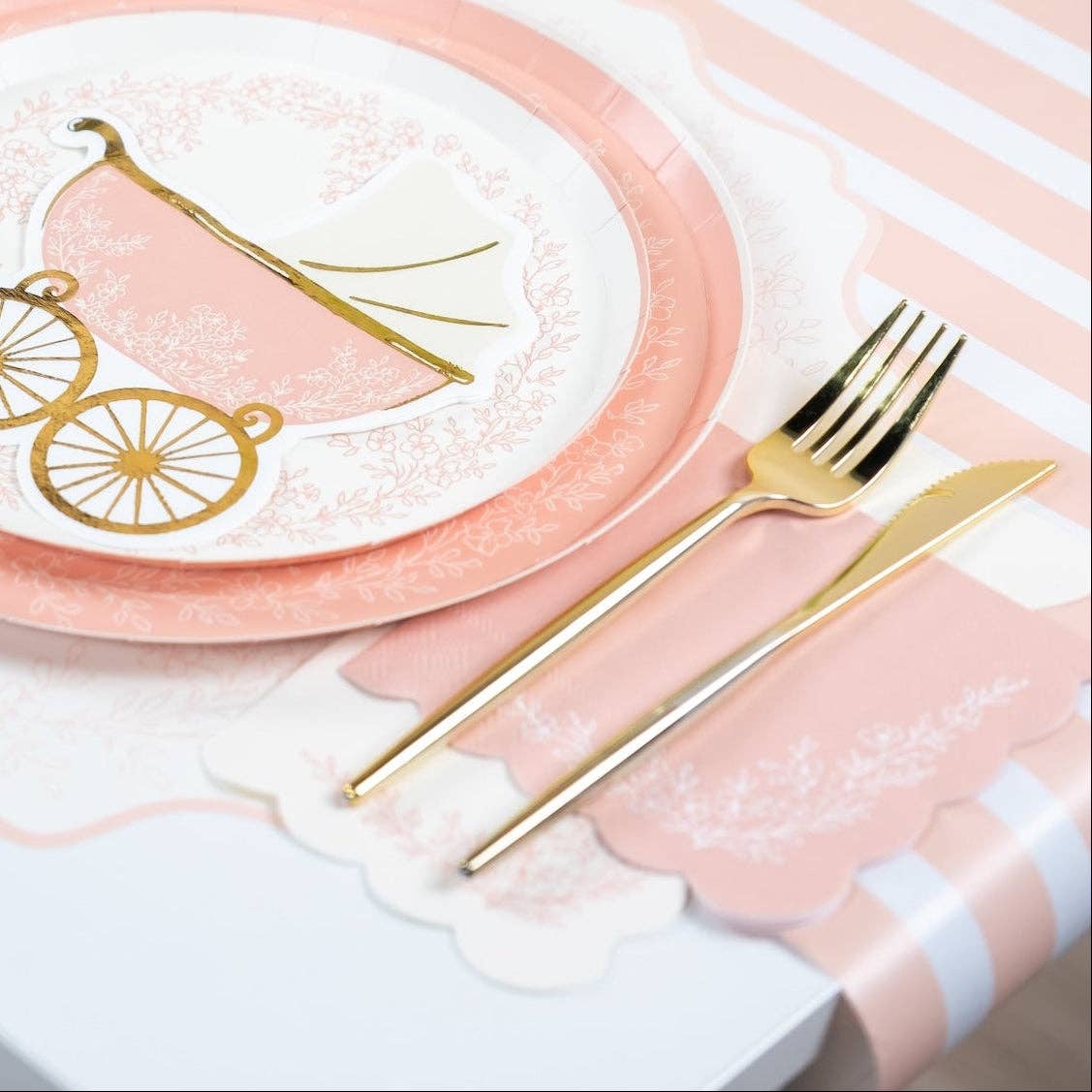 Pink floral guest towel styled under gold cutlery on a striped tablecloth