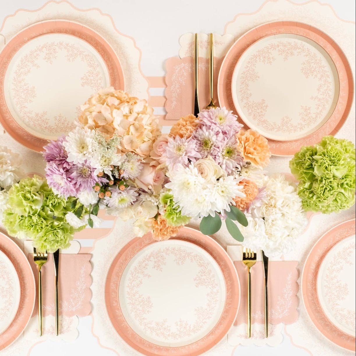Overhead view of a party table featuring pink floral placemats and fresh flower centerpieces