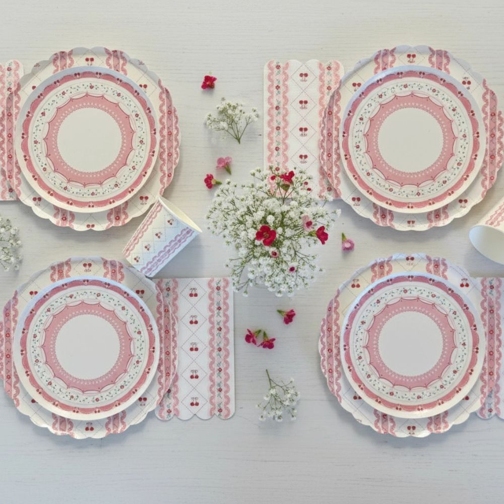Flat lay of four cherry place settings with floral centerpieces on white wood