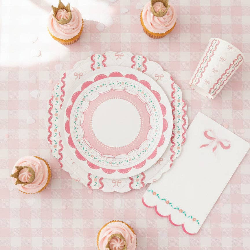 Bow-themed cup on a pink gingham tablecloth with crown cupcakes