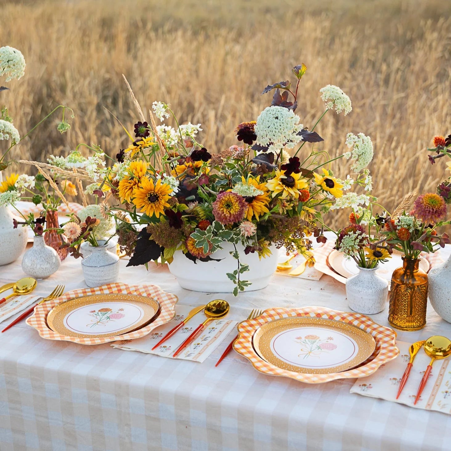 Outdoor fall tablescape with cozy floral dessert plates, gold flatware, and wildflower centerpiece.