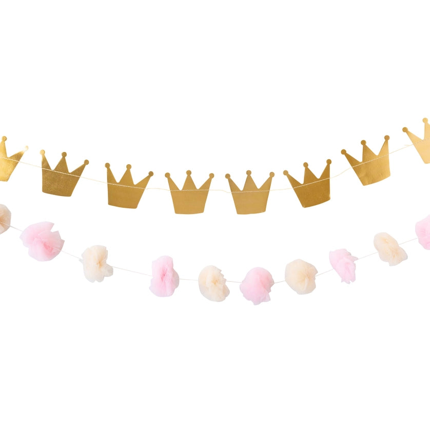 Isolated view of double garland set—upper row of gold foil crowns, lower row of alternating pink and cream tulle poms on white background.