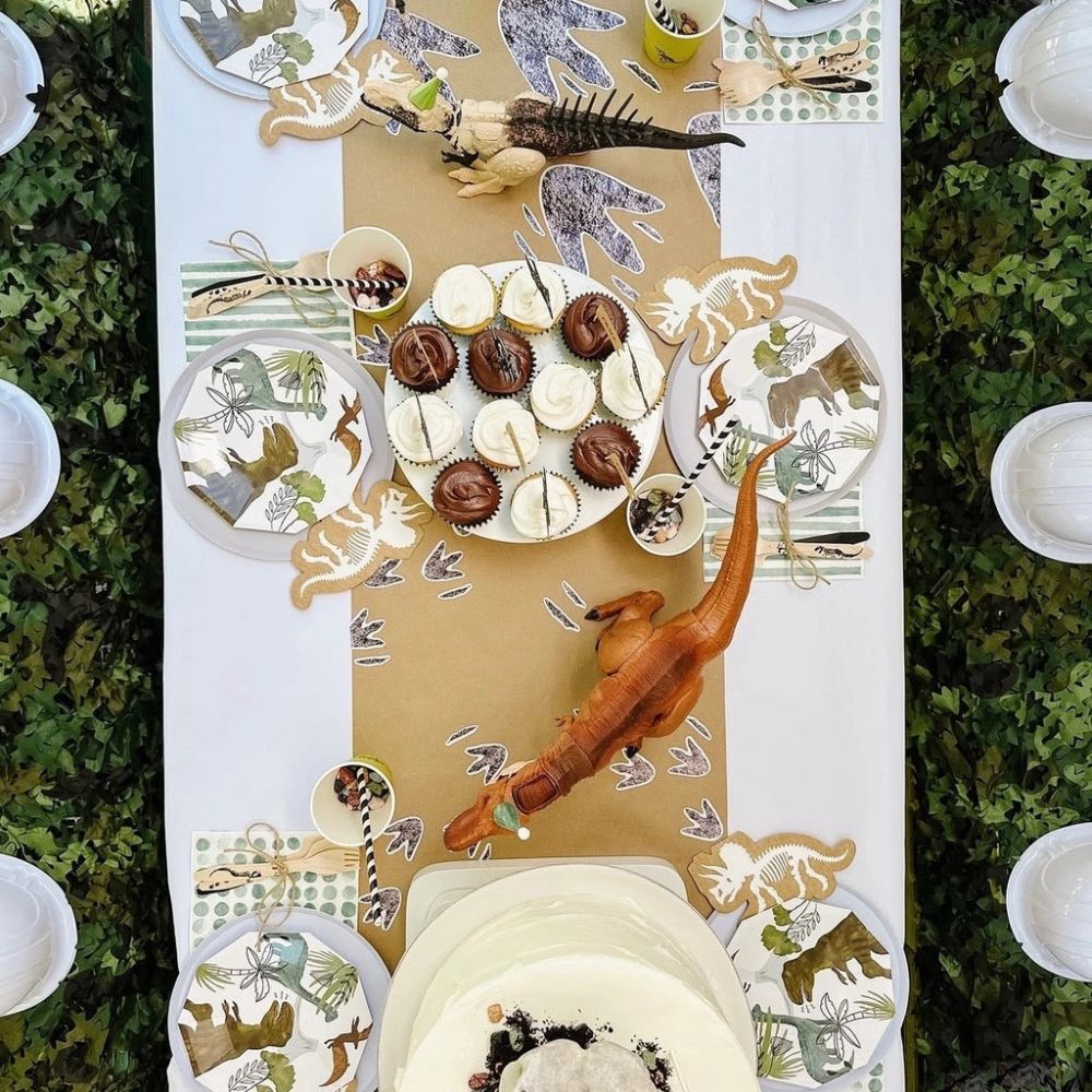 dinosaur party table setup with pastel plates and themed decor
