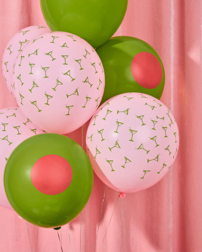 Pink martini print and green olive latex balloons floating in front of pink curtain backdrop showing both designs inflated