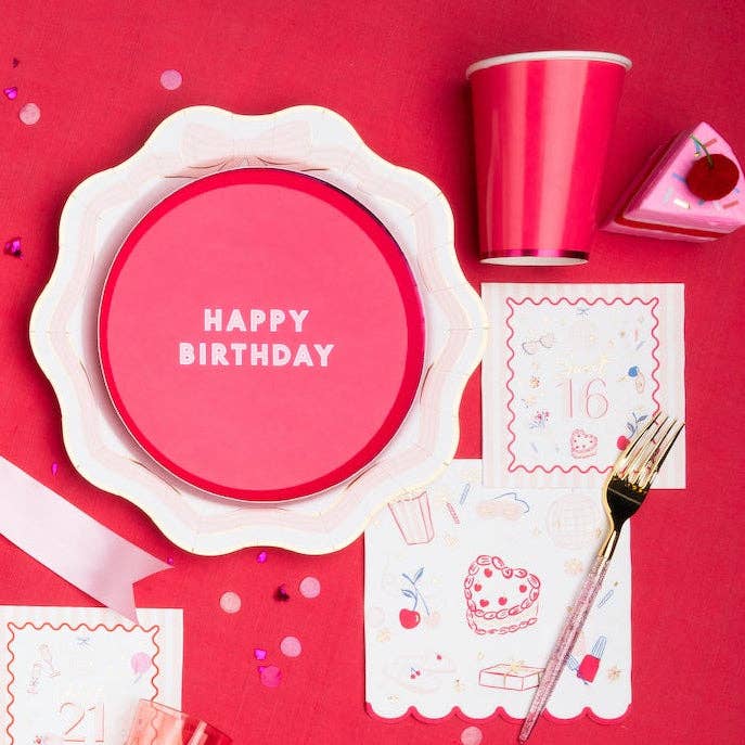 Pink and red 16th birthday table setting with Sweet 16 icon cocktail napkins, a pink scalloped plate, and a gold party cup.