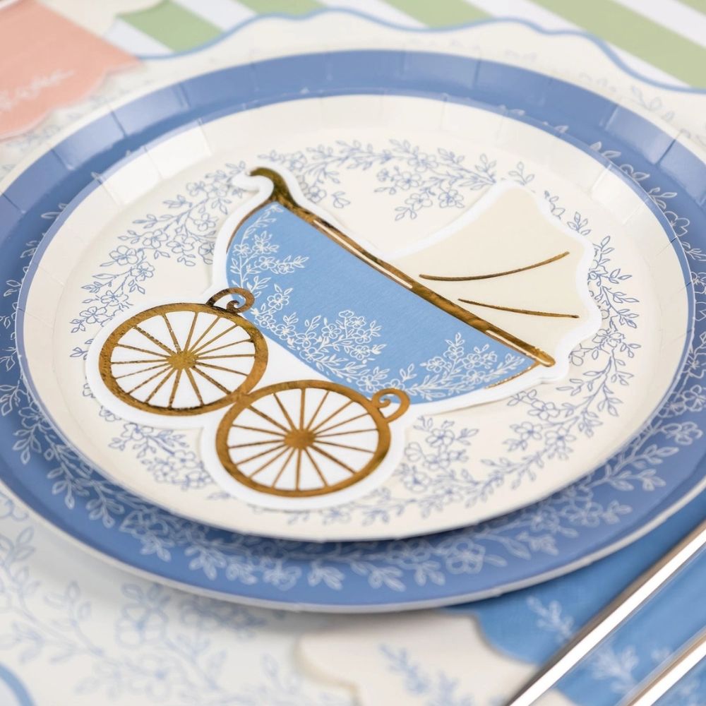 Dusty blue dinner plates styled on a floral table setting with a baby carriage napkin.

