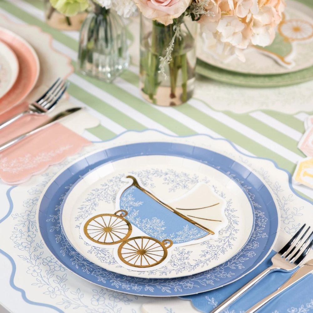 Dusty blue dinner plates styled on a floral table setting with a baby carriage napkin.
