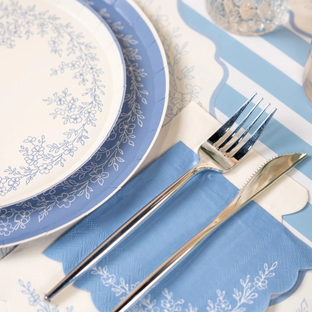 Dusty blue guest towels layered under silverware and floral dinner plates.

