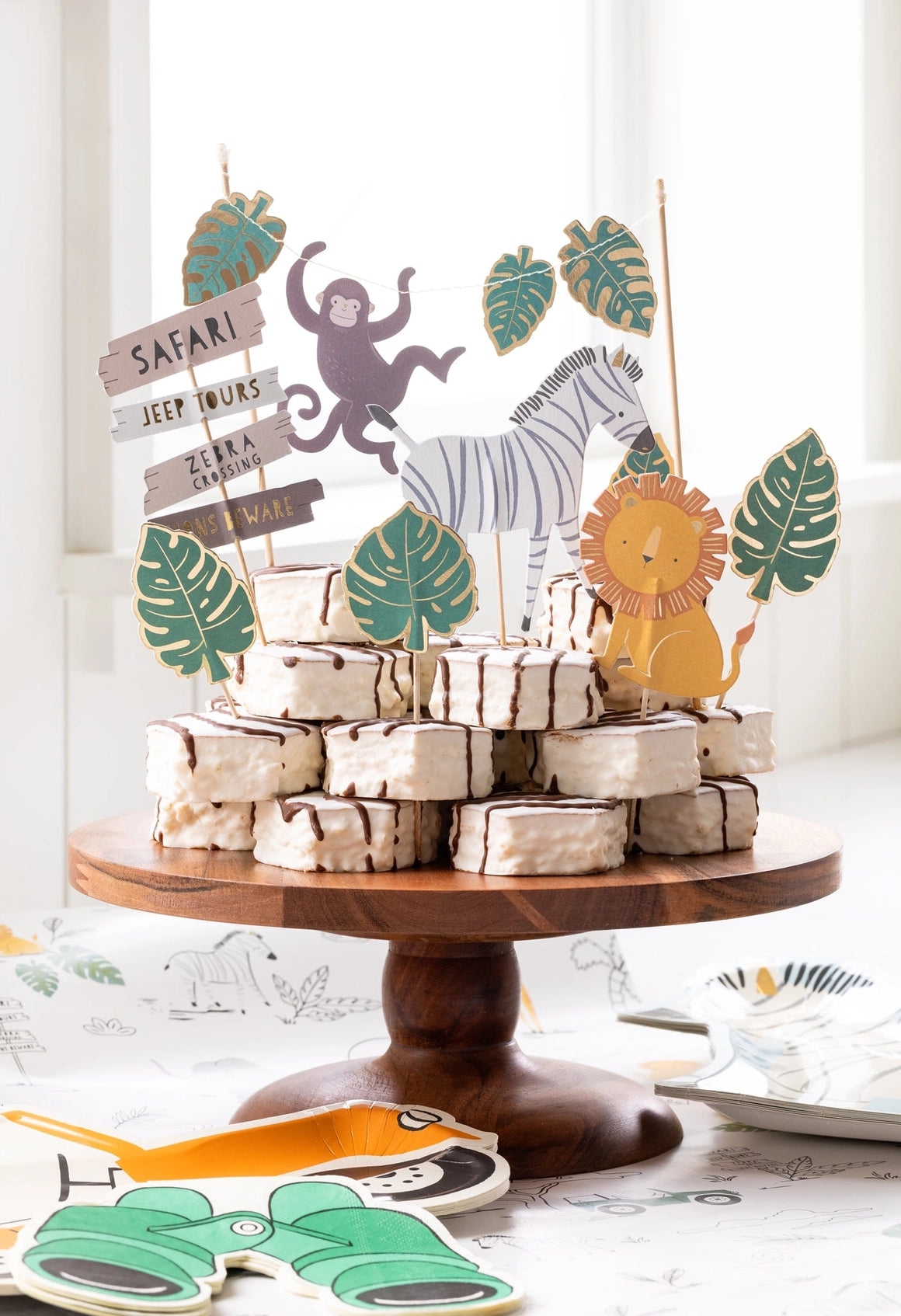 Close-up of safari animal and leaves cake toppers decorating white-frosted treats.