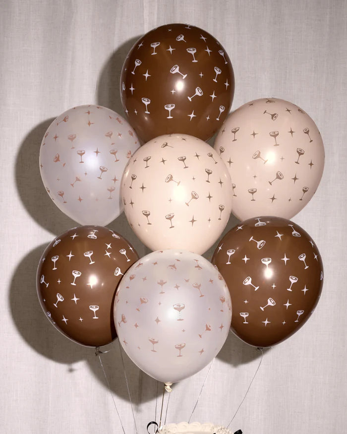 Full balloon bouquet of eight espresso martini print matte latex balloons in chocolate brown, cream, and blush against a white linen backdrop