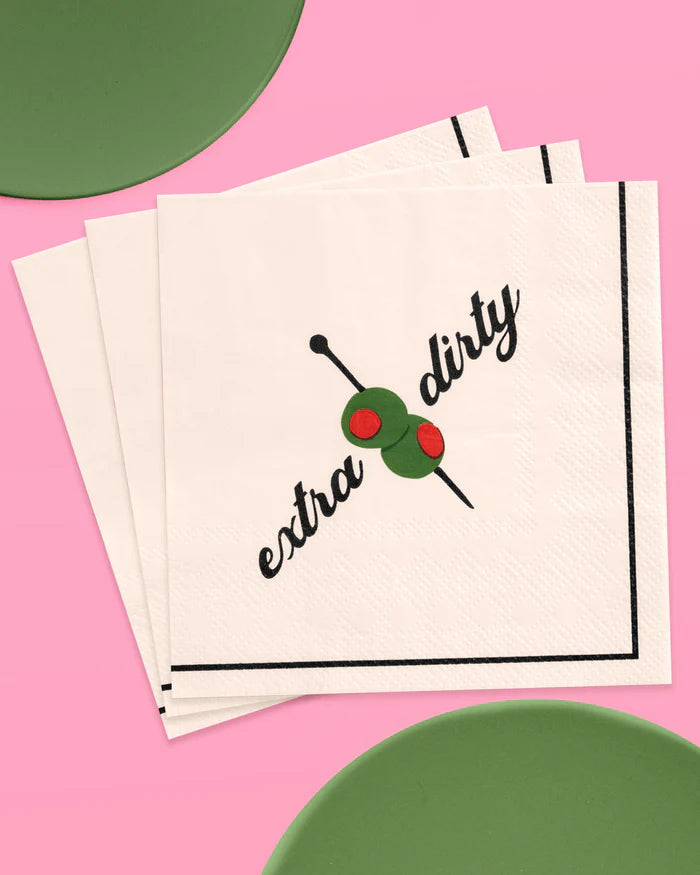 Fanned stack of extra dirty martini paper cocktail napkins with green plates on a pink background