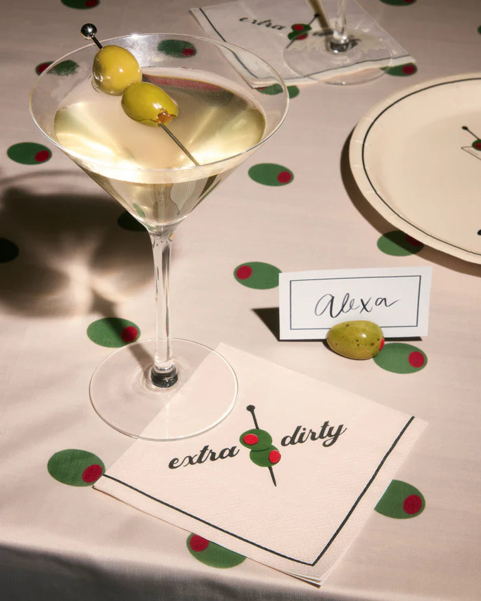 Extra dirty martini napkin under a cocktail glass on a styled tablescape with place card and olive confetti