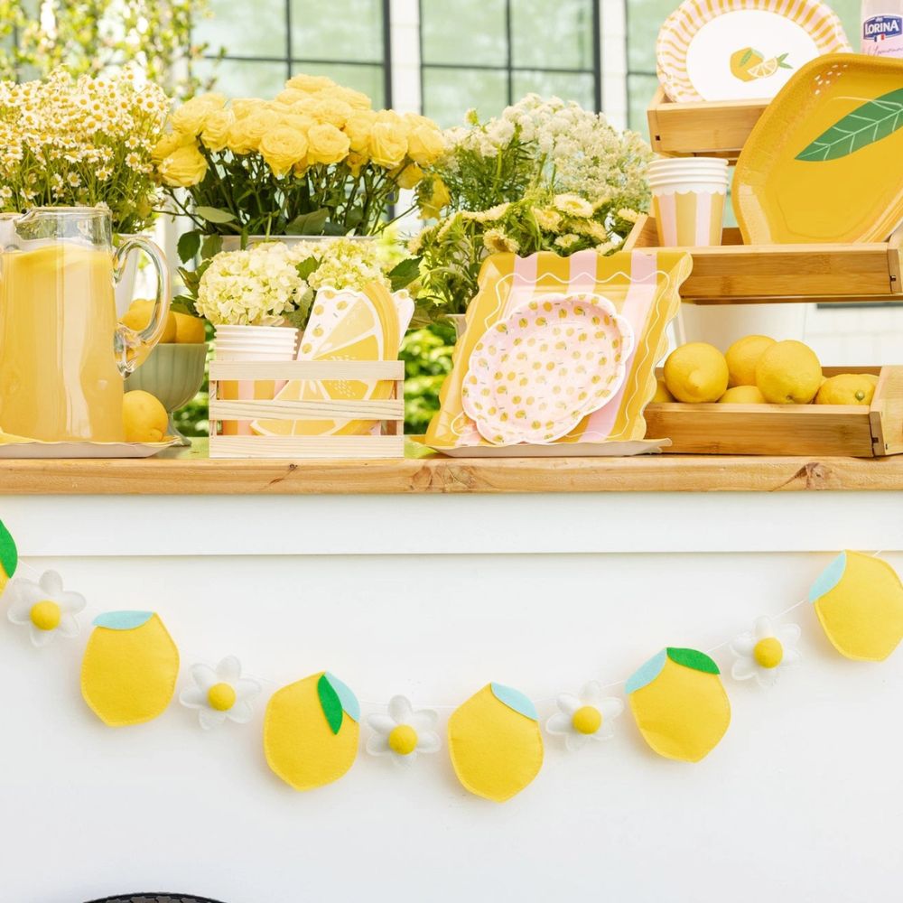 lemon banner styled across table with yellow party decor and lemonade setup.
