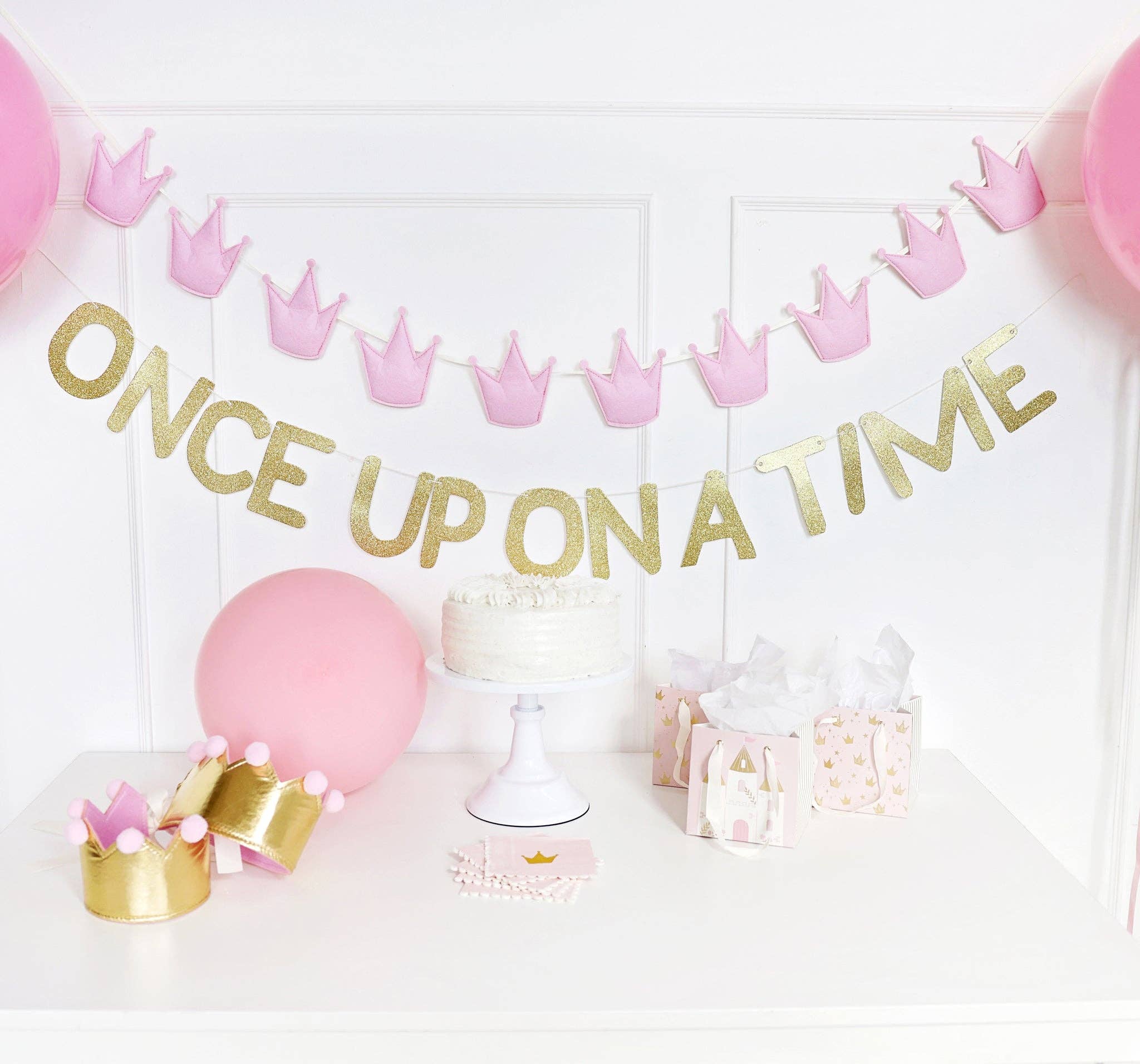 A Once Upon a Time Banner styled above a cake table with pink balloons for High-End Fairytale Decor.