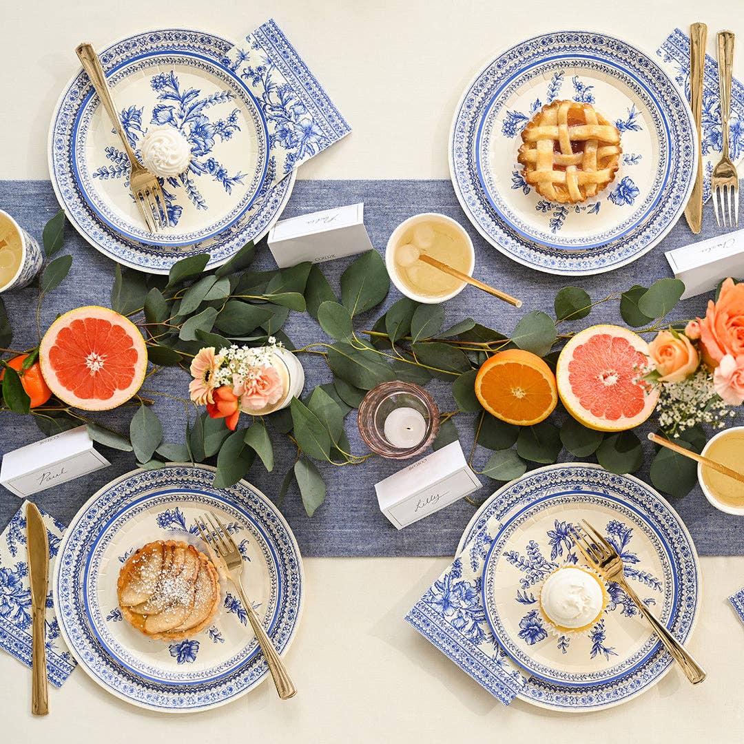 French toile plates styled on table with greenery and citrus decor