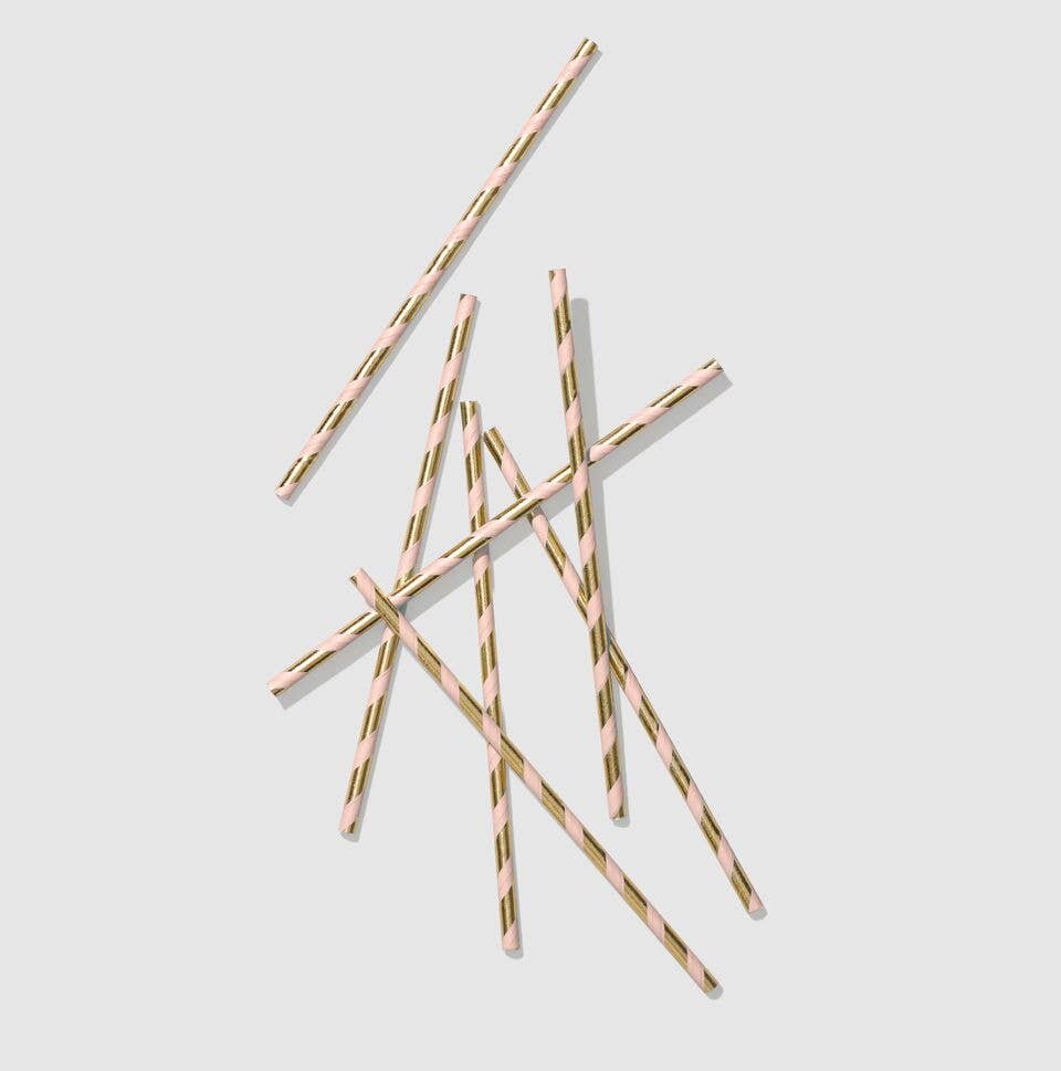 Scattered pink and gold foil striped paper straws on a grey background showing the high-quality metallic finish.