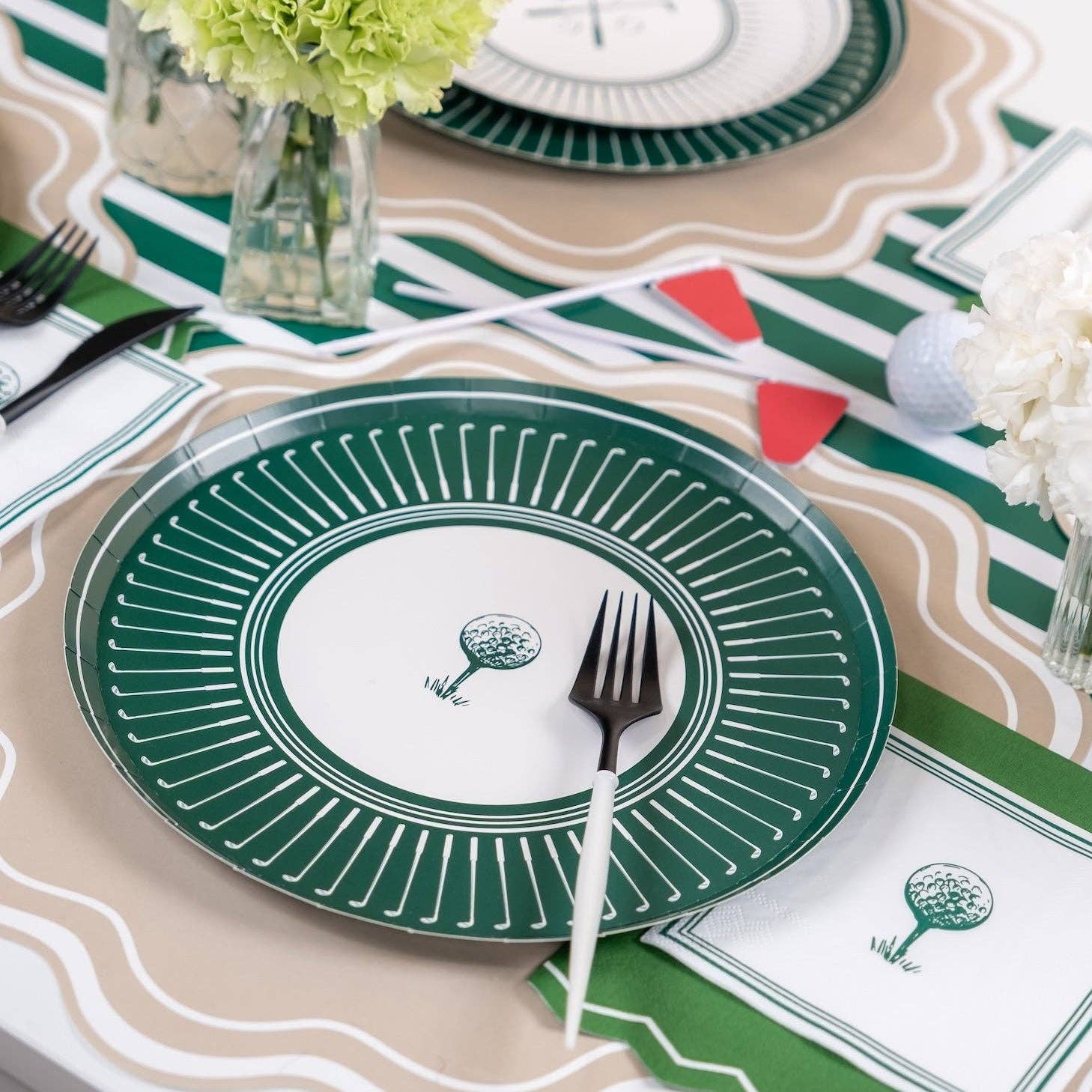 A lifestyle close-up of a golf party plate paired with a black fork and scalloped placemat, styled for a sophisticated sports-themed luncheon or birthday.