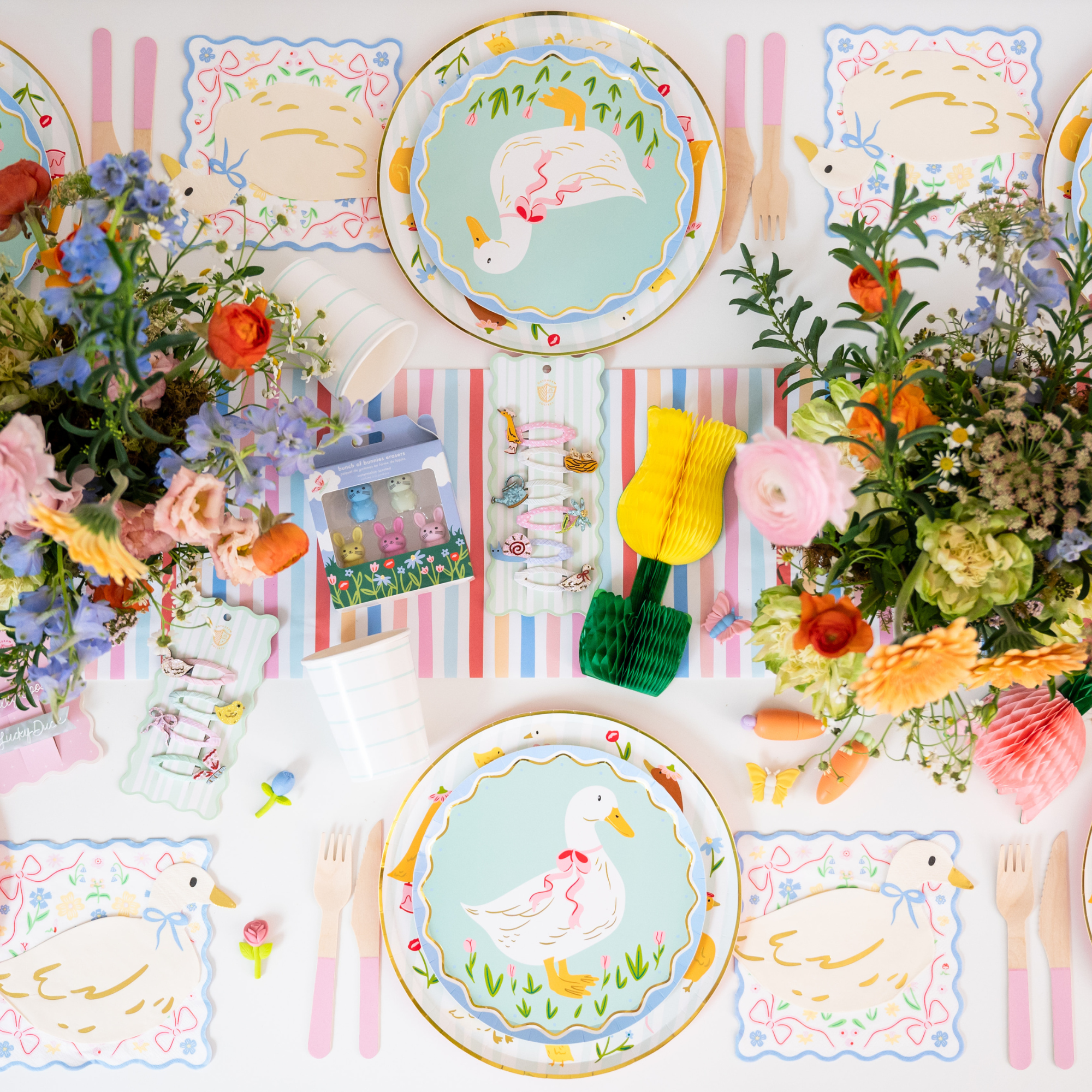 Colorful spring party table setup with goose themed tableware and decorations.