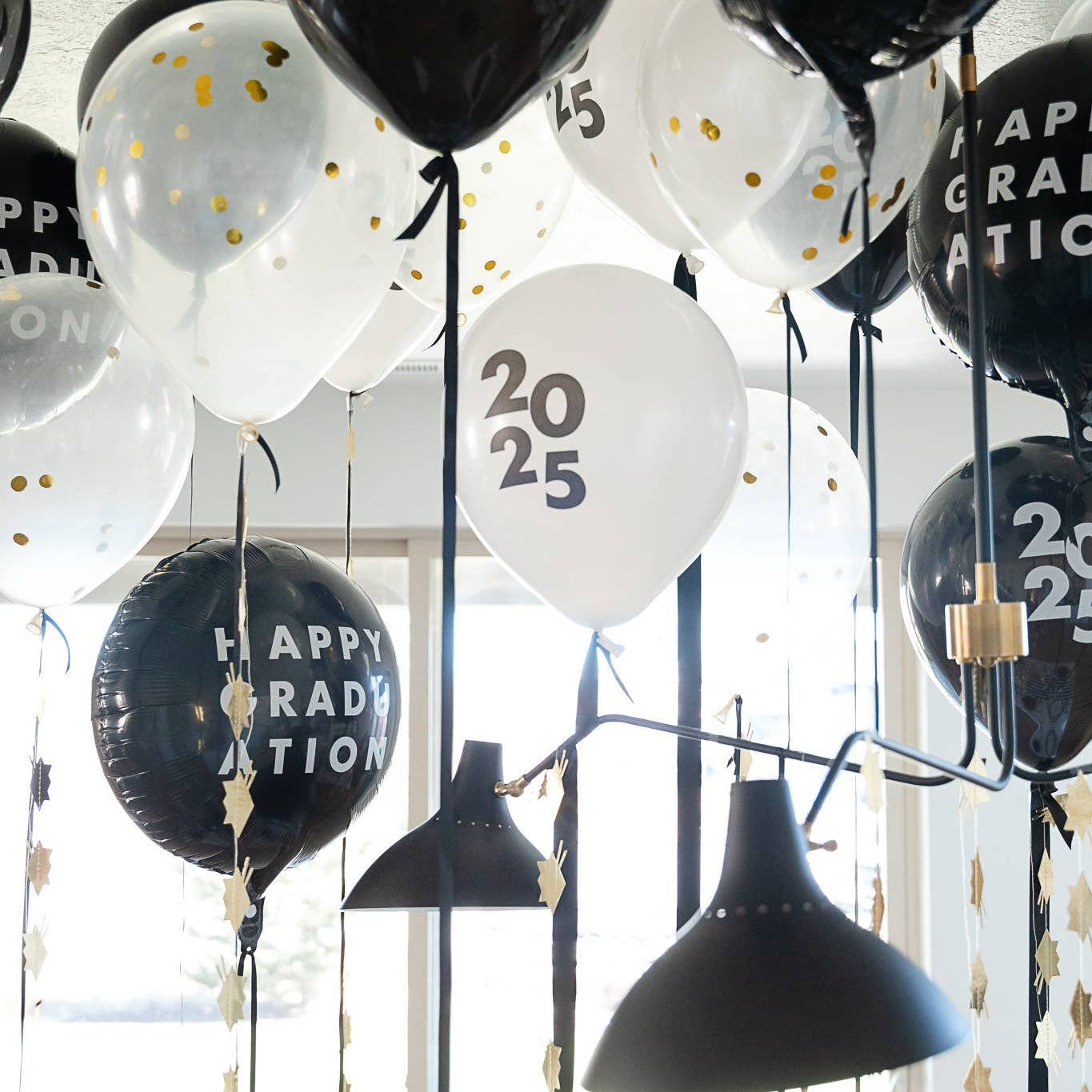 Graduation balloons with gold hat garland hanging from ceiling