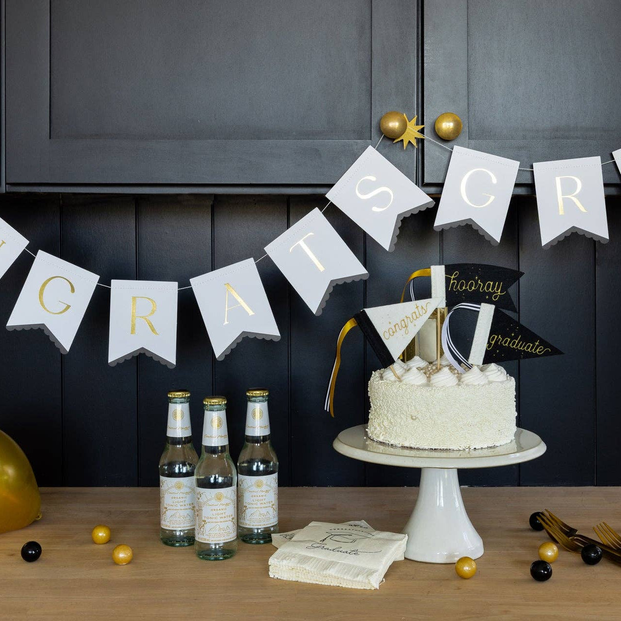 Graduation party setup with gold balloons cake toppers and congrats banner decor
