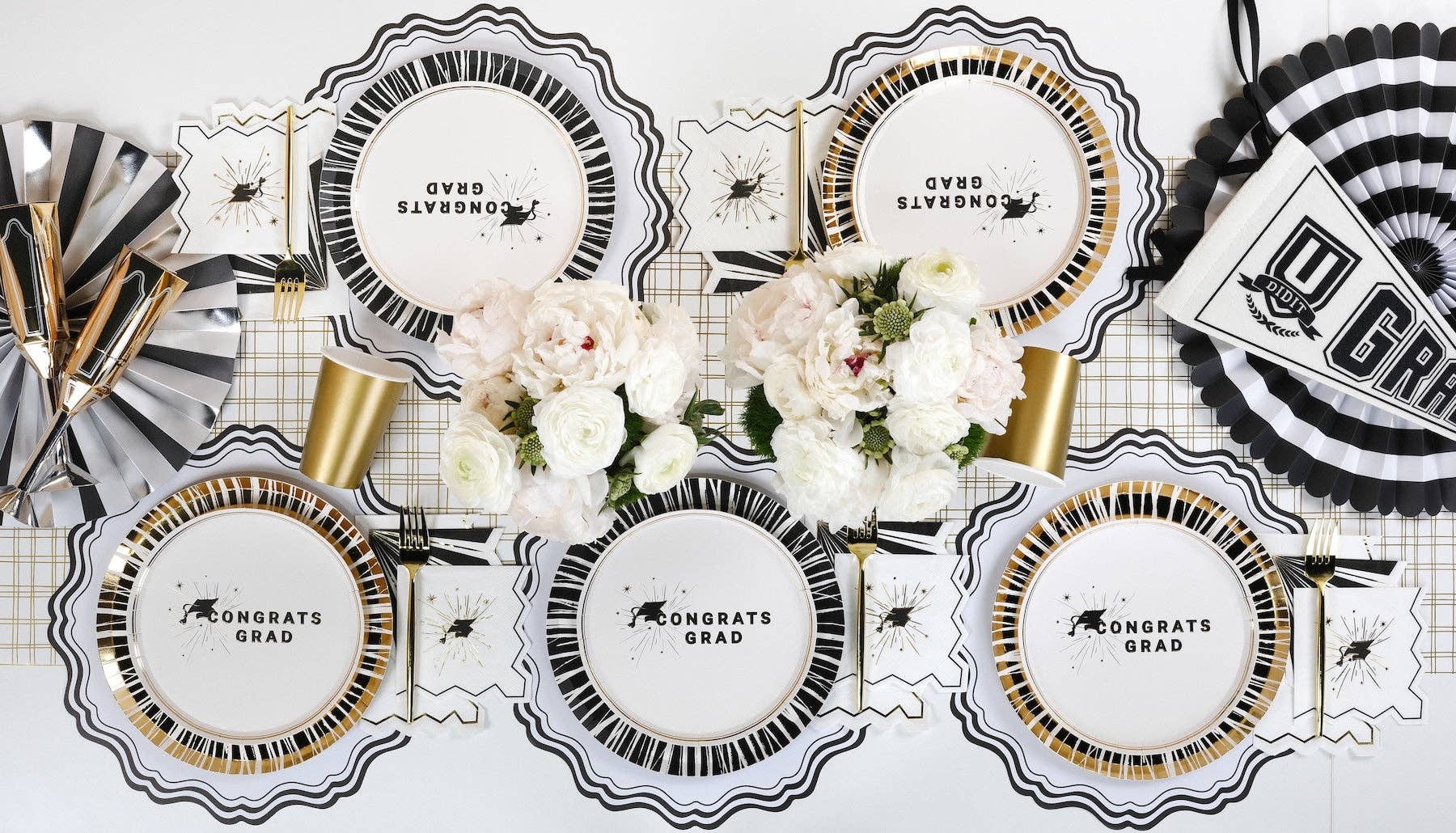 A close up of a Congrats Grad dessert plate with a gold foil striped rim for a Cap and Champagne celebration