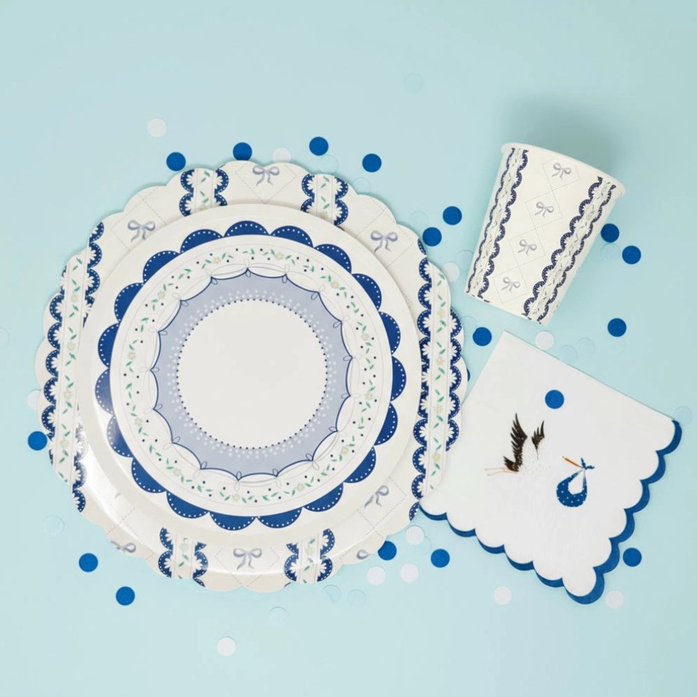 Overhead view of a stork napkin, blue ribbon cups, and plates on a turquoise background