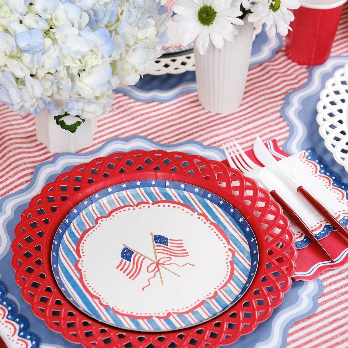 Detailed view of a Patriotic Guest Towel framing a flag plate on a red latticed charger.