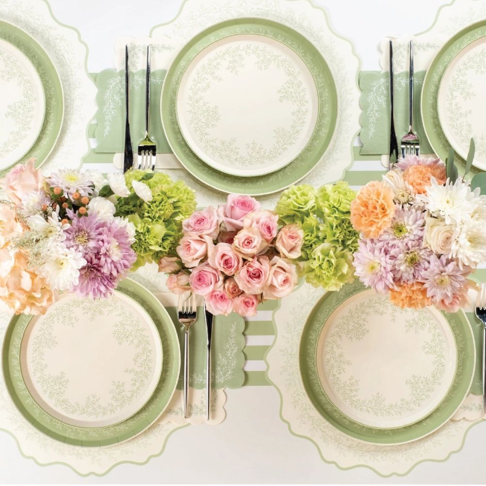 green floral paper placemats arranged with flowers and tableware.