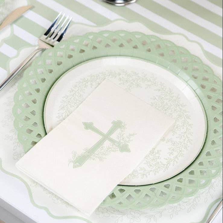 A close-up of a Botanical Cross guest towel resting on a floral paper plate with a sage green lattice border.
