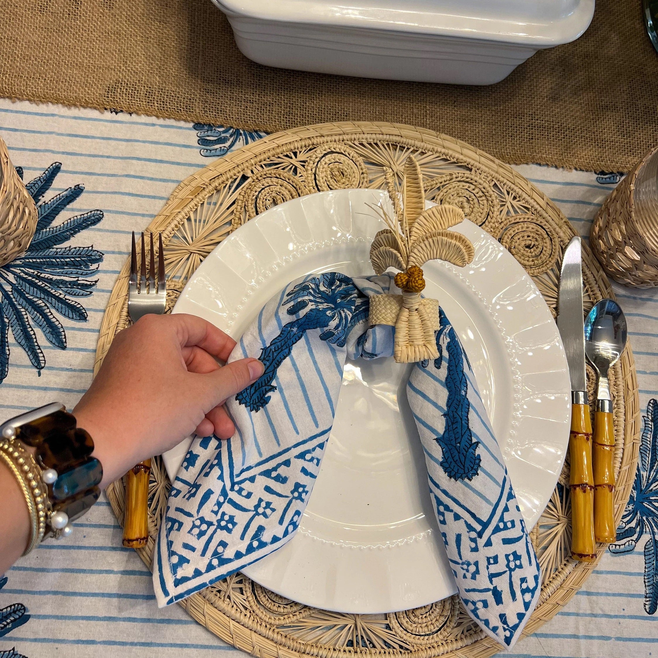 Escape to the tropics at every meal with our woven Palm Tree Napkin Rings. Crafted to complement your tropical table decor, these napkin rings feature natural-colored palm trees with brown coconuts, adding a coastal touch to your table. Perfect for hosting a luau or simply spicing up dinner, these palm tree napkin rings offer an instant vacation vibe.