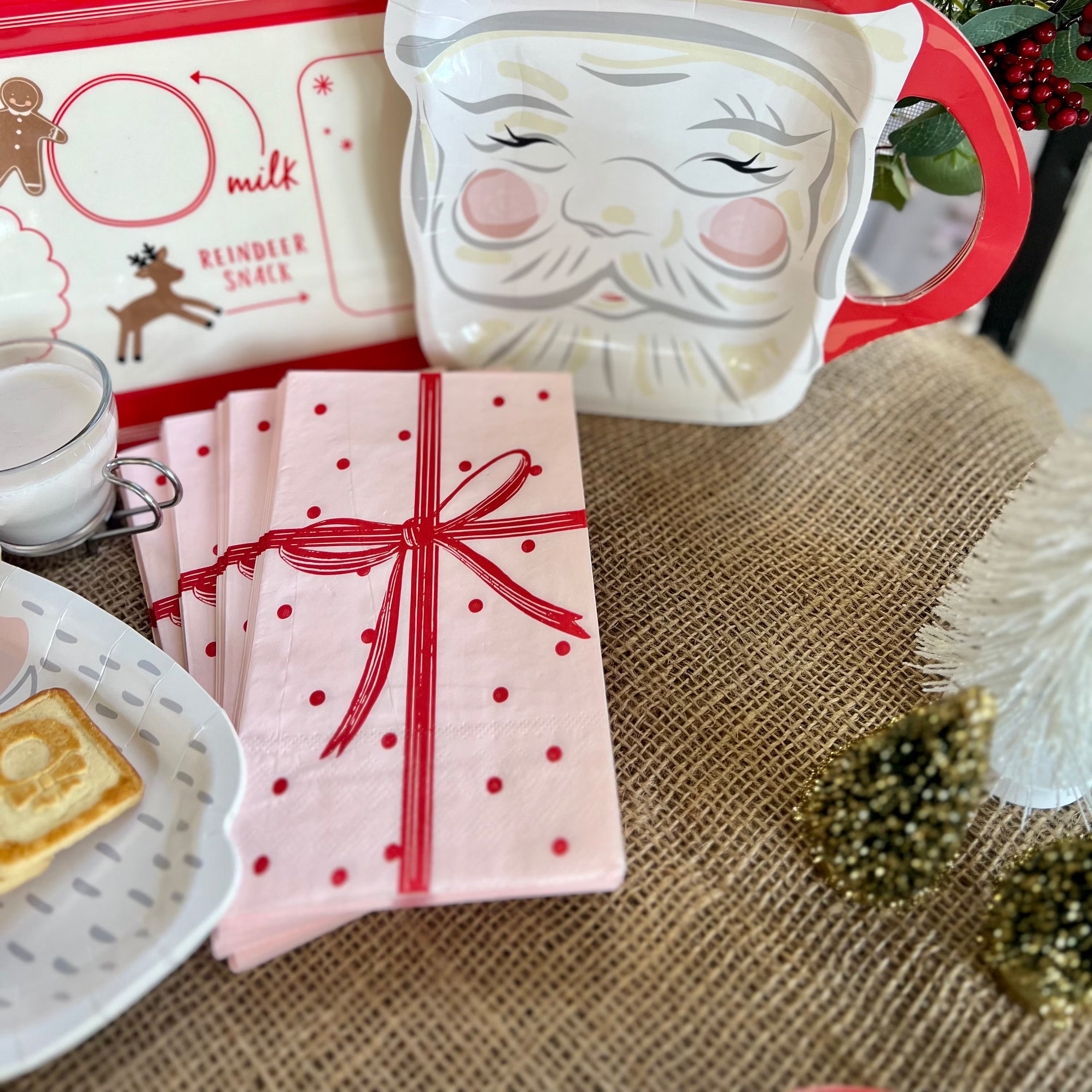 Paper Christmas napkins shaped like a pink wrapped gift with a red bow.