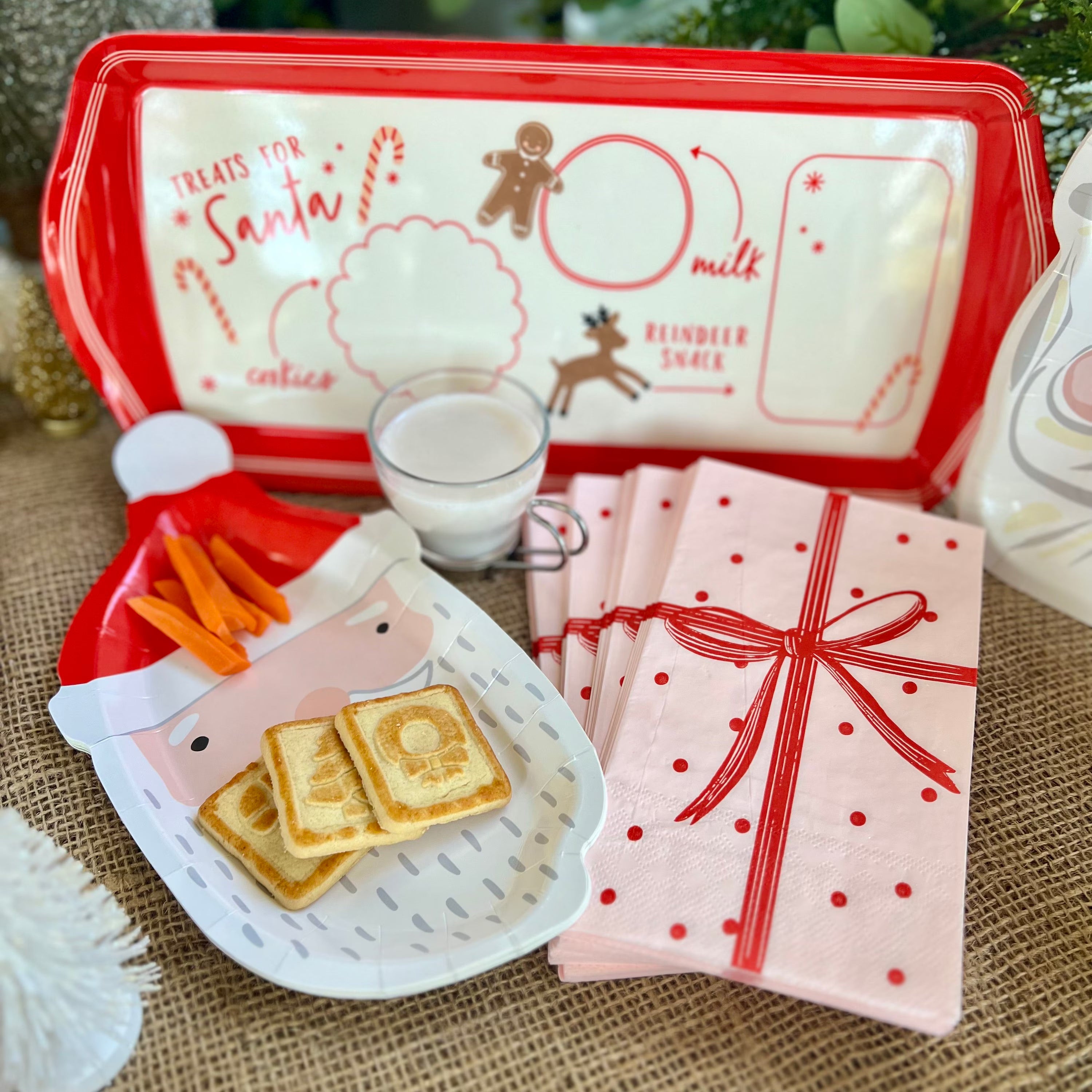 Paper Christmas napkins shaped like a pink wrapped gift with a red bow.