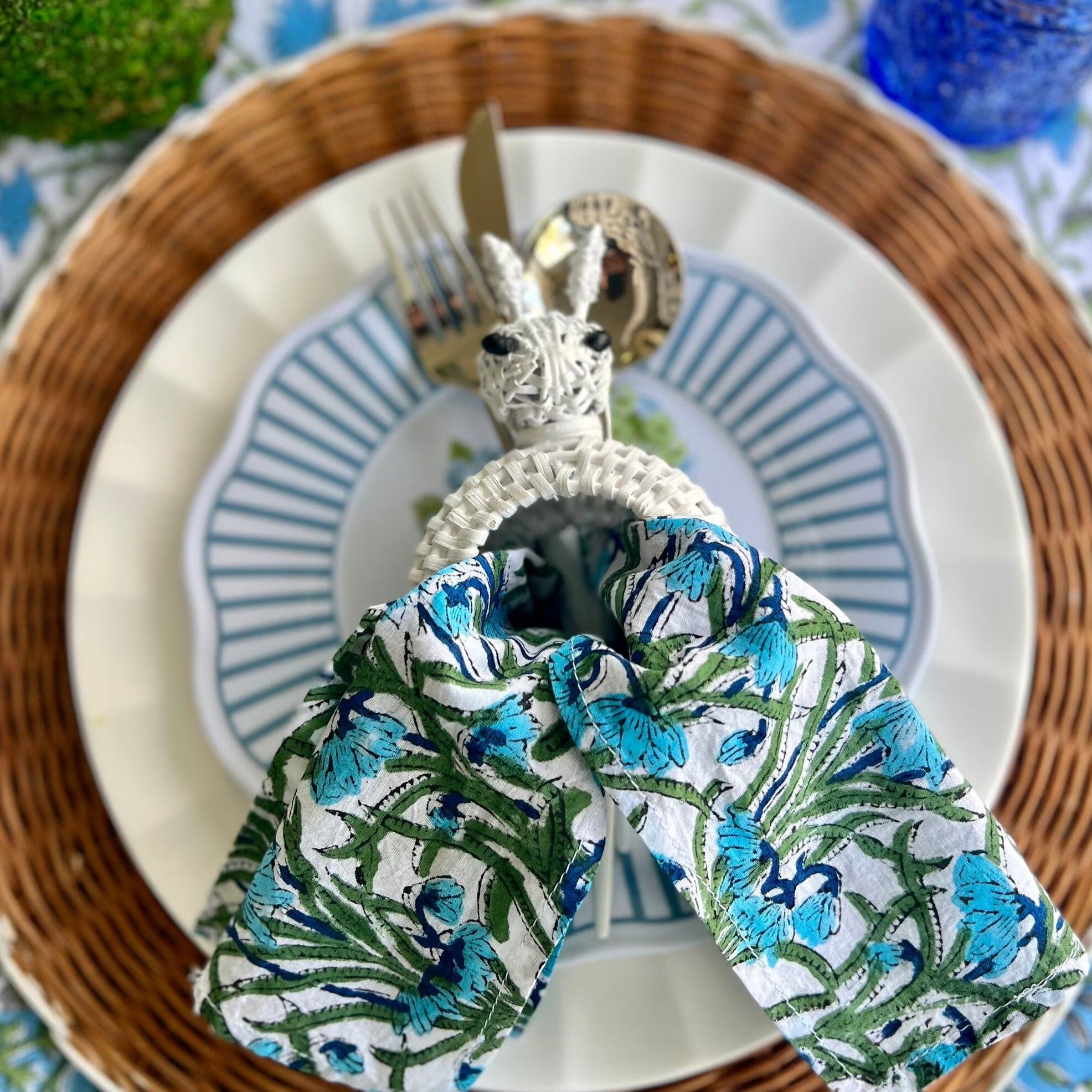 White wicker bunny Easter napkin ring on a blue easter tablescape - its perfect for a preppy, classic Easter look.