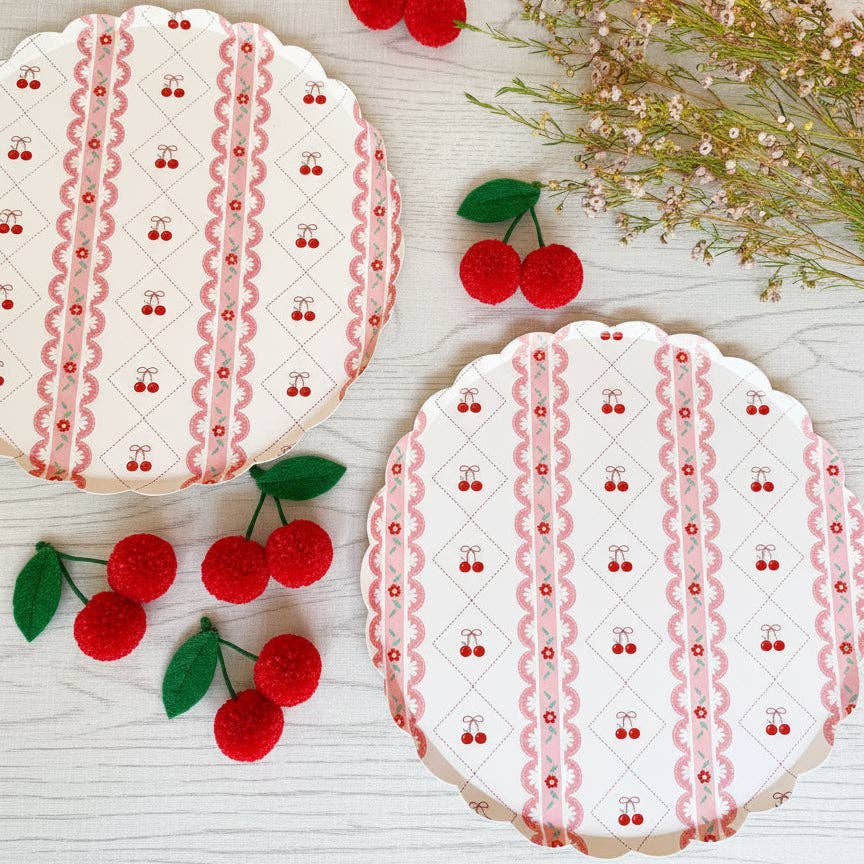 Overhead view of two cherry plates on a white wooden surface with cherry props