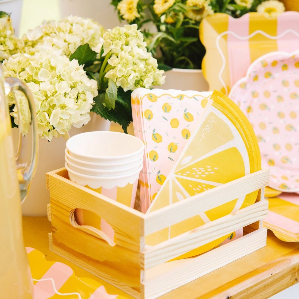 Lemon themed party setup with napkins, cups, and floral decor
