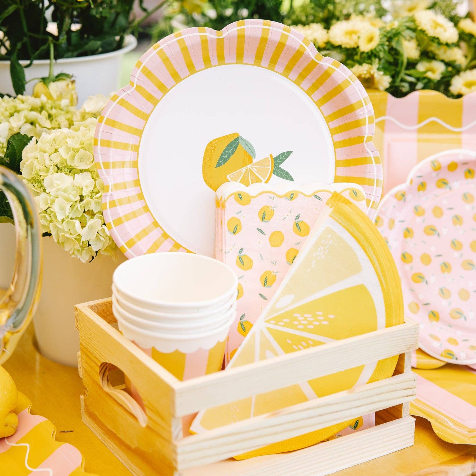 Lemon party setup with plates, cups, and citrus decor in crate