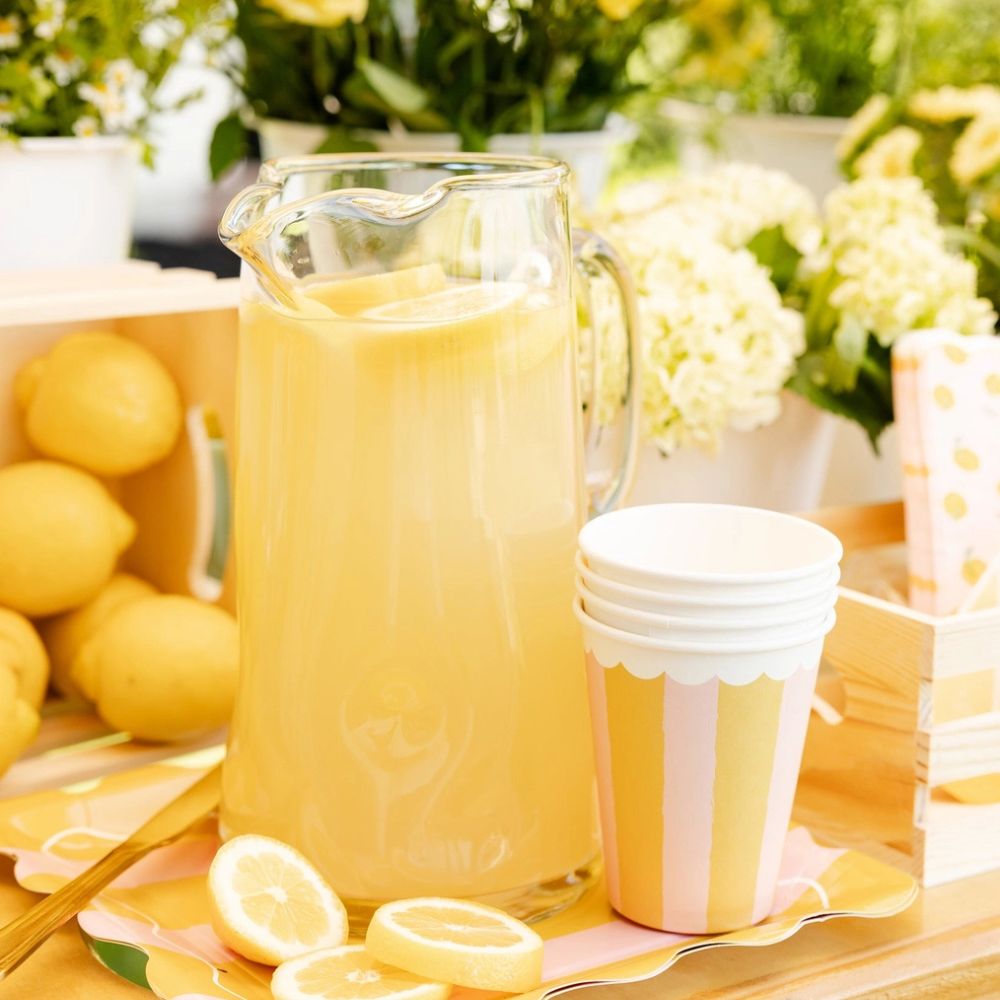 Lemonade pitcher with yellow striped party cups on summer table