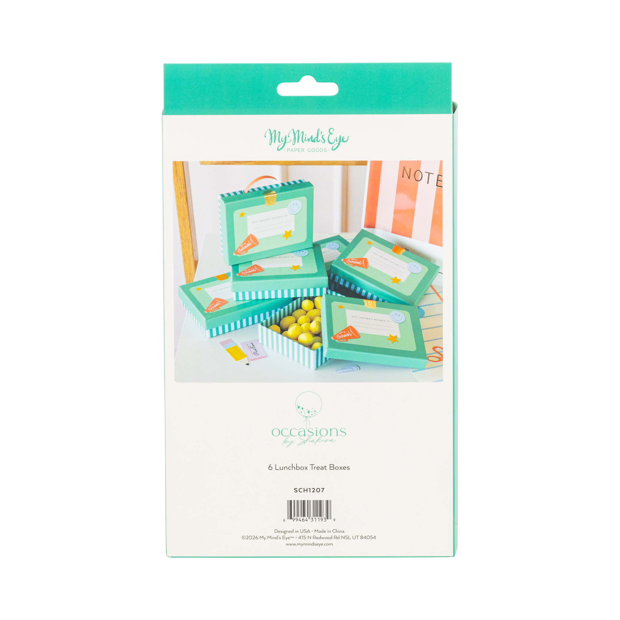 Back of lunchbox shaped treat box packaging showing styled product scene with teal boxes stacked and filled with yellow candies on white desk
