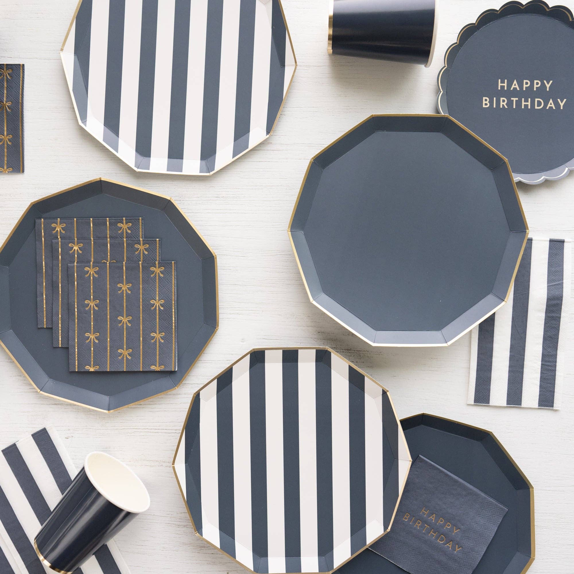 Styled tablescape (stripes): Navy blue and striped party plates with coordinating cups and napkins on white tabletop.