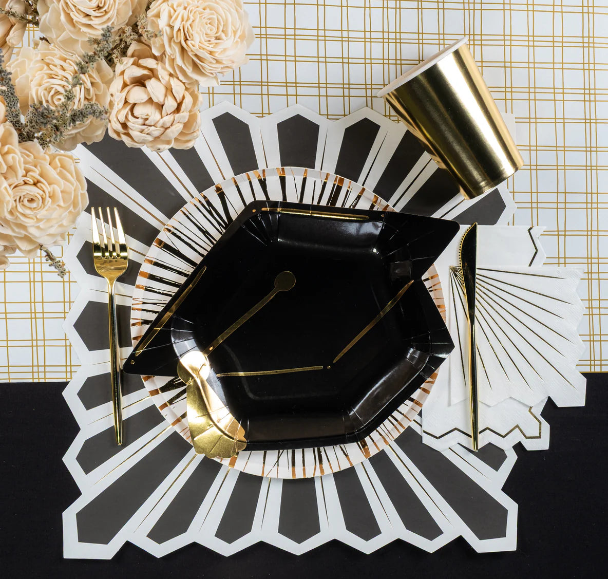 Close view of black plate stack and white napkin with gold starburst detail.